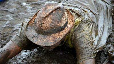 A music fan lies in the mud at the V Festival in Staffordshire