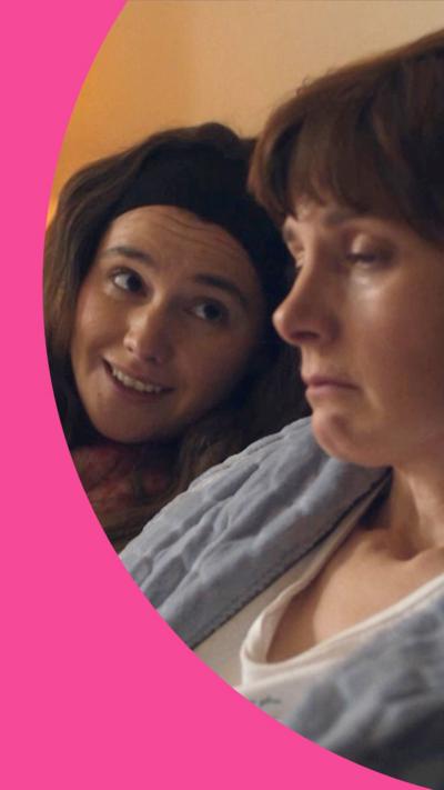 A woman, Billie, smiles at her mum, Deb, who looks sad in bed