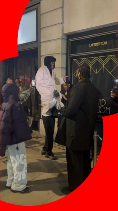 A man sits on the shoulders of another man to appear taller. 