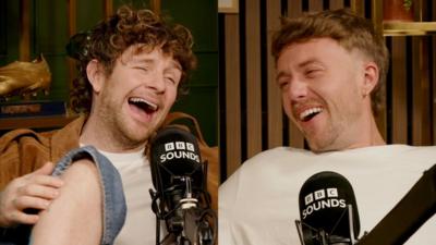 A composite image showing two young men laughing while sitting behind microphones.