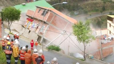 Rescuers watch a house collapse