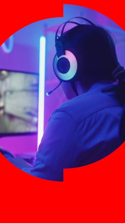Female gamer wearing headphones and  looking at a screen.