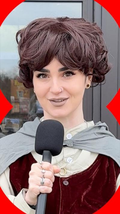 A woman in LOTR cosplay speaks into a mic