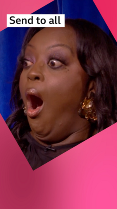 Judi Love looks shocked. She is wearing a brown dress and gold earrings. She has long, wavy black hair.