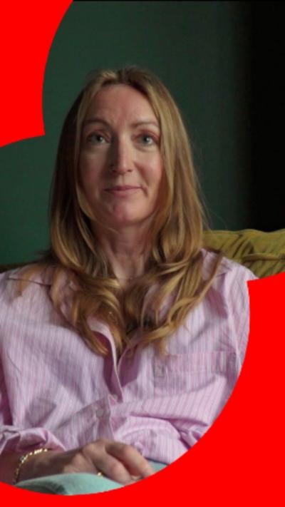 A woman with long blonde hair and a pink shirt sat on a yellow sofa