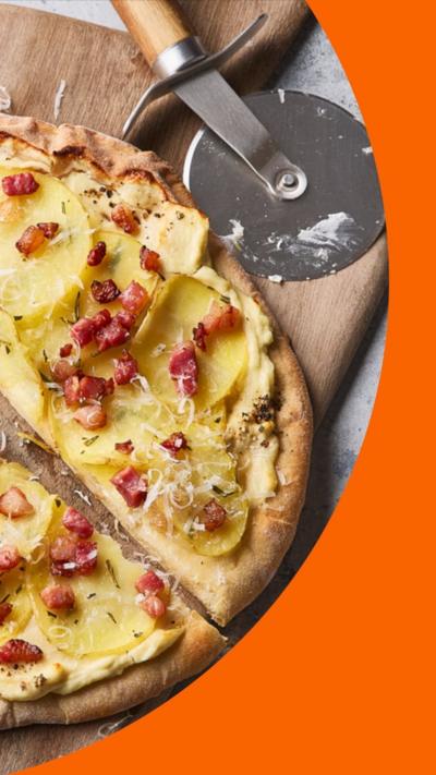 A top-down image showing a potato pizza cut into slices on a table.