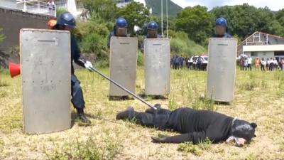 A man dressed in a bear costume is lying down after being subdued by police in an animal attack drill.