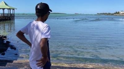 Young man looking at the oil spill on the beach