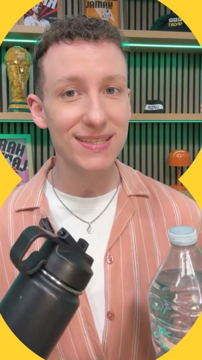 Harry Hansen looks at the camera and smiles. He holds two water bottles - a black reusable one and a clear plastic one.