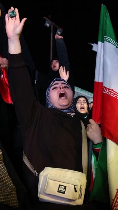 A woman holding her hand and an Iranian flag up