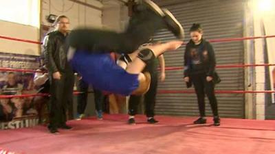 Trainee wrestler doing a back-flip at a gym.