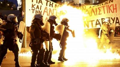 Riot police stand amongst flames from petrol bombs thrown by a small group of anti-establishment demonstrators in Athens