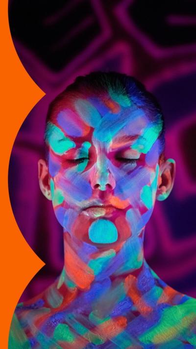 A woman with her face and shoulders covered in different coloured strokes of neon paint. She has her eyes closed