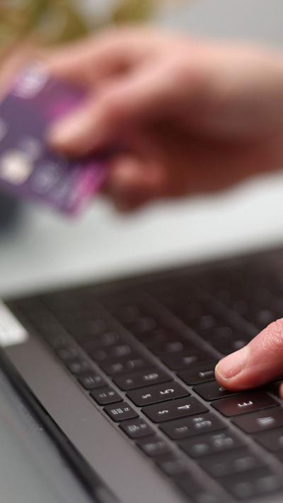 A person's hands using a laptop as they hold a bank card.
© PA Media