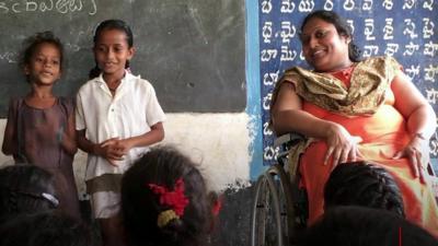 Sai Padma, right, sits in her wheelchair in a classroom full of children