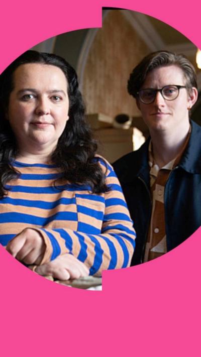 A woman with black curly hair wearing a blue and pink striped top.