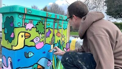 Artist Kev Munday paints a junction box