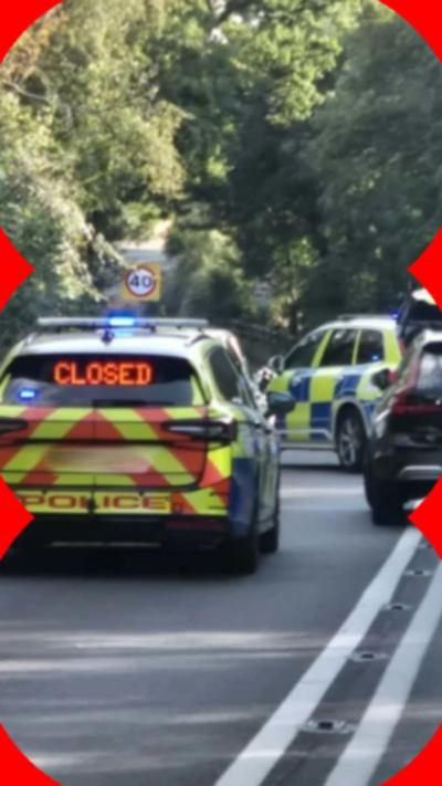 Police cars parked in the middle of a road. One of the cars has the word "closed" written in lights in the back window.