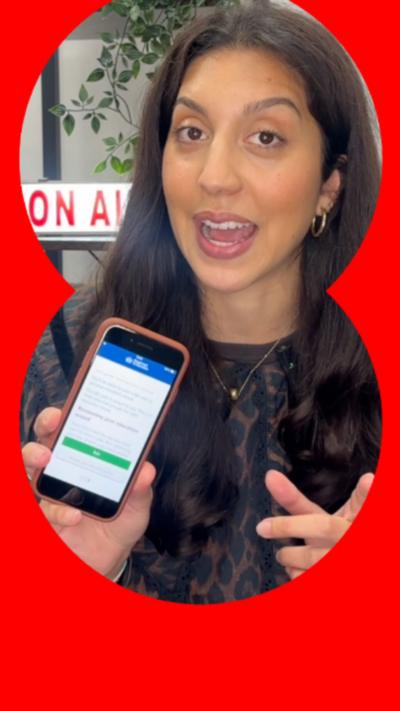 A woman with brown hair holds up an iPhone showing an app.
