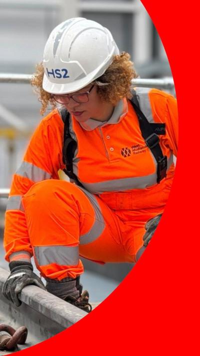 Woman in white hard hat with 'HS2' written on the front. She's also wearing an orange high-vis suit 