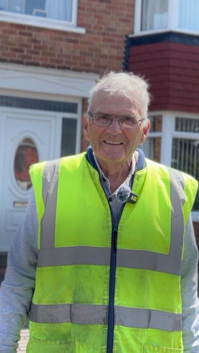 Man wearing a hi-vis jacket in front of a terrace house
