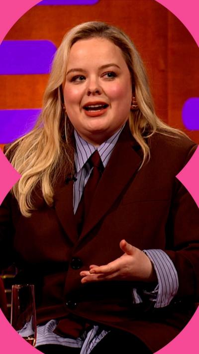 Nicola Coughlan wears a suit and tie, she has long blonde hair