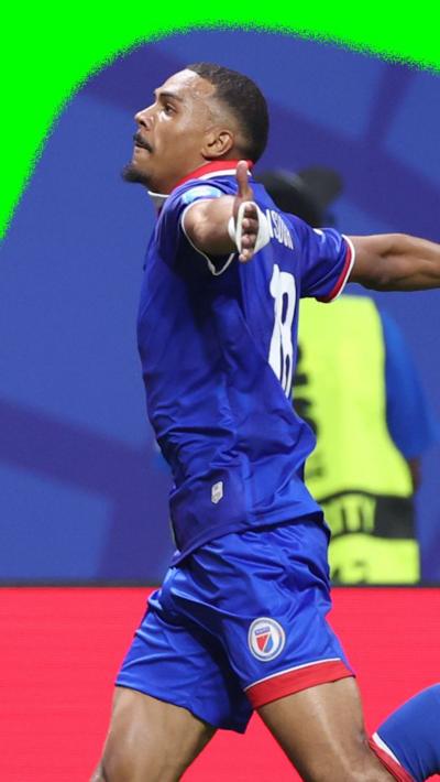 Wilson Isidor runs to the crowd with his arms wide open to celebrate scoring a second goal for Haiti