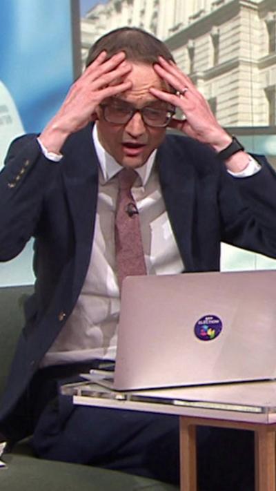 A male reporter with his hands on his head in shock