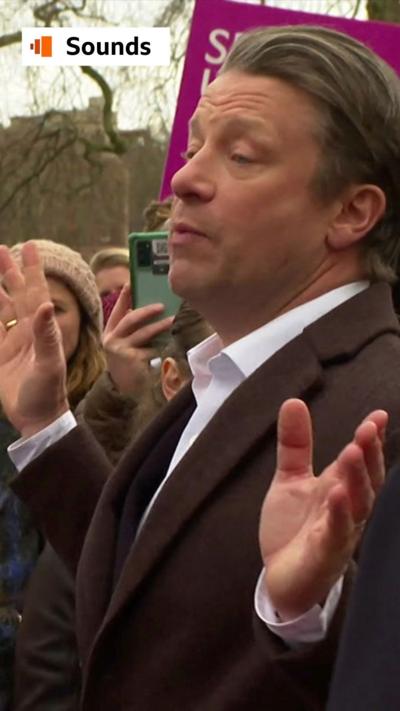 Jamie Oliver speaks to a crowd in a park