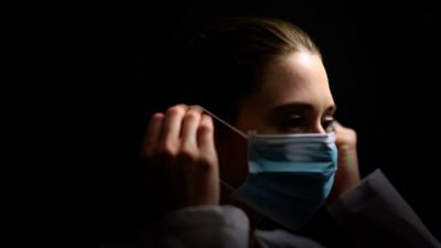 A woman putting a face mask on