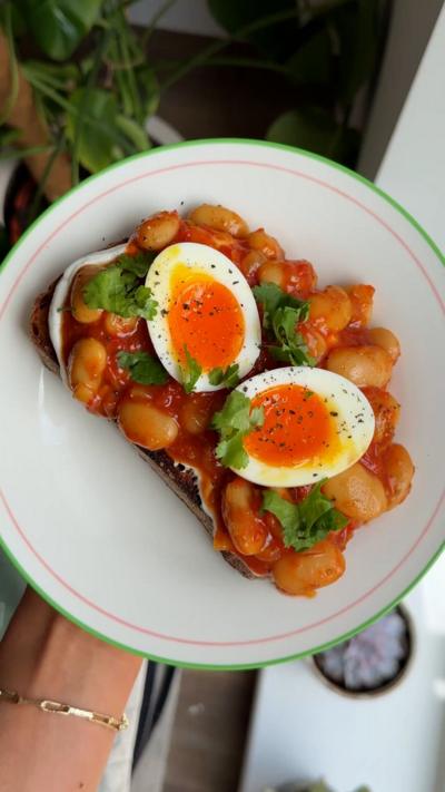 Masala beans with jammy egg on a white plate from above