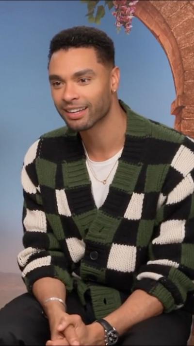 Rege-Jean Page in a green, white and black chequered cardigan