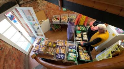 Community larder. Boxes of fruit, bread and vegetables are in shot.