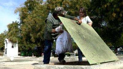 Skeletal remains are put into a pit in Greece