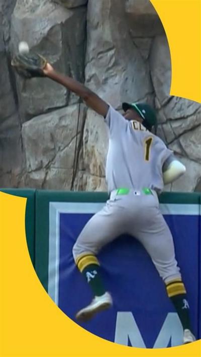 Man in baseball uniform stretches to catch ball