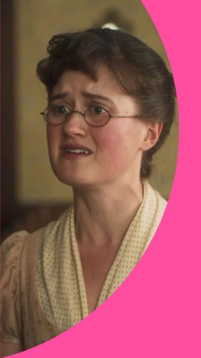 A young woman with brown hair looks distressed. She has rounded glasses and is wearing an old-fashioned cream coloured dress.