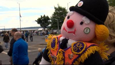 Knitted orange order style doll with an orange sash and black bowler hat