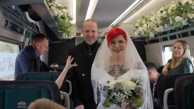 Vince Smith and Leah Anderson walking down the train aisle