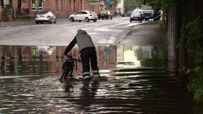 Cyclist walks through a puddle