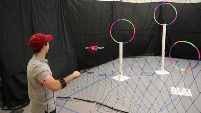 A man controls a drone using sensors on his arm