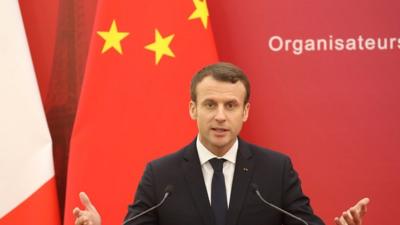 Emmanuel Macron speaks in front of Chinese and French flags