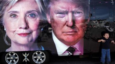 A boy gestures next to a backdrop of US Democratic presidential nominee Hillary Clinton and her Republican counterpart Donald Trump at the Hofstra University, in Hempstead, New York