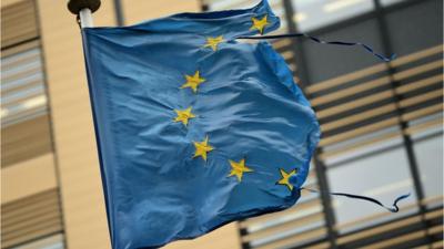 A shredded European Union flag flutters in the wind in Brussels