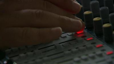 Hand on mixing desk in radio studio