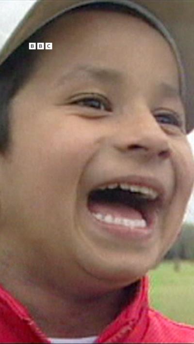 A young boy with a white cap and red jacket laughing