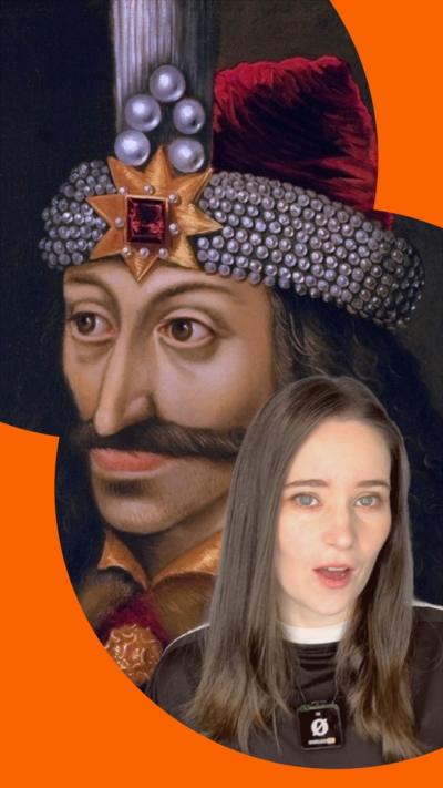 A woman in a black t-shirt with a mic clipped on to her is seen with a drawing of Vlad the Impaler behind her. He is wearing a red hat which has various gems on it.