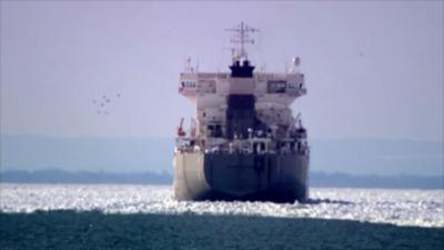 Shot from behind, a large cargo ship is stuck, surrounded by ice on Lake Erie