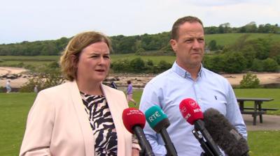Evelyn McLoughlin and Kevin Cooley speaking in front of microphones.