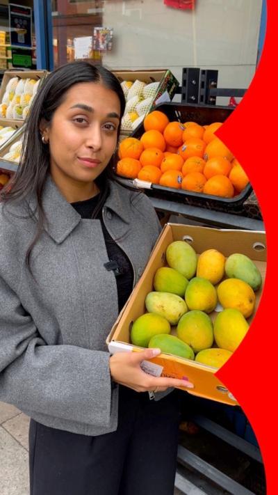 A woman holding a box of mangoes