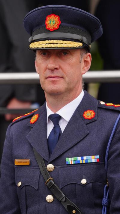 Garda Commissioner Justin Kelly stands in his uniform while attending an event. He is an older man with no facial hair. His uniform is dark blue and has several badges pinned to the front.